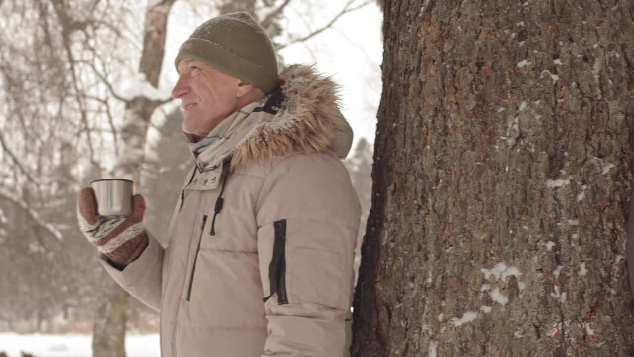 um casal a desfrutar de bebidas quentes num parque coberto de neve.