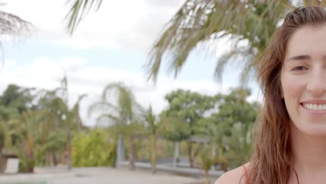 retrato de una feliz mujer caucásica mirando a la cámara sobre las palmeras.