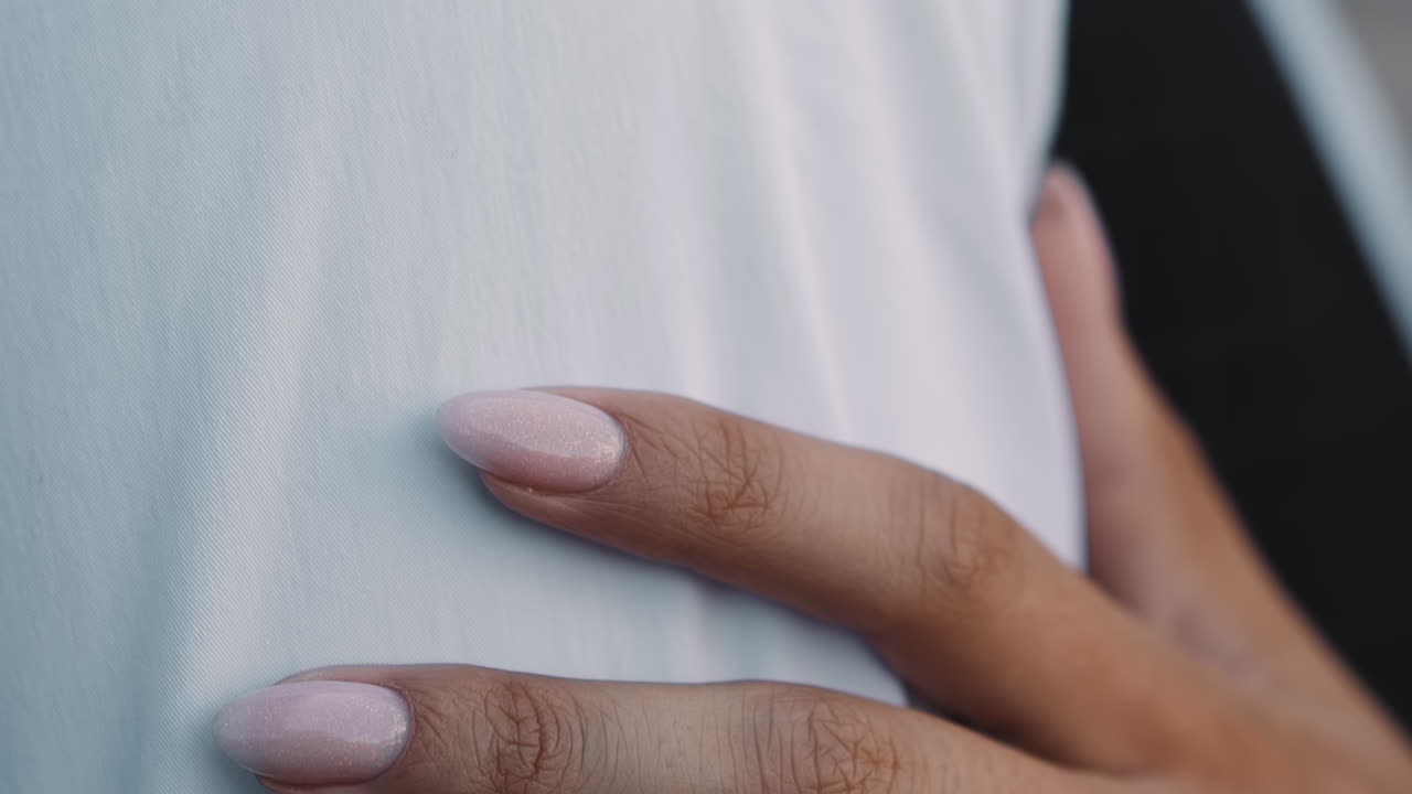 Young wife hand with manicure touches shoulder of groom