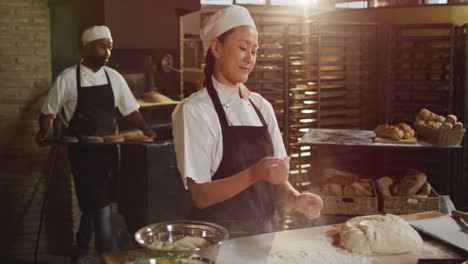 Animation-of-happy-asian-female-baker-clapping-hands-to-clean-flour