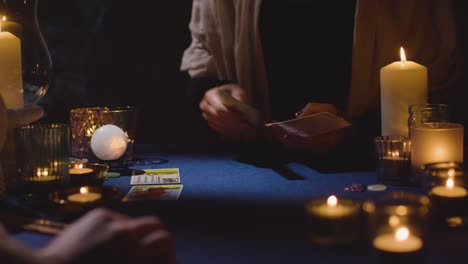 primer plano de una mujer dando una lectura de cartas de tarot a un hombre en la mesa a la luz de las velas 4