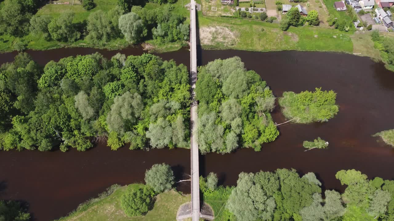 vuelo aéreo sobre un río con un puente en un pequeño pueblo ukmerge, lituania