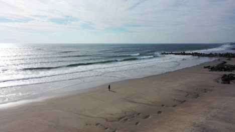 Una-Vista-De-Drones-Sobre-Una-Playa-Tranquila-Con-Una-Persona-Caminando-Por-La-Mañana