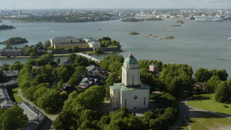 aerial view away from the church, at the suomenlinna fortress, pikku-musta island in the background, sunny, summer day, in helsinki, finland - reverse, tilt up, drone shot