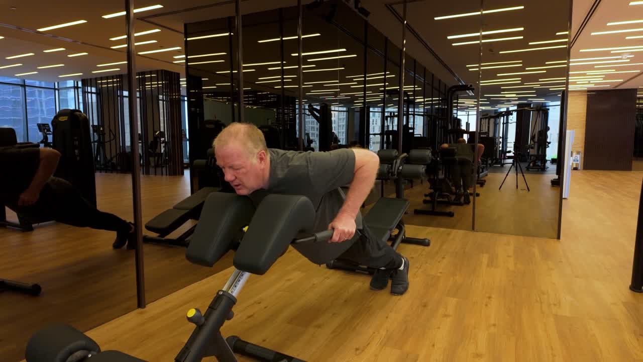 Elderly Caucasian Man Doing Push-ups On A Exercise Machine In A Indoor Gym, Slow Motion Shot