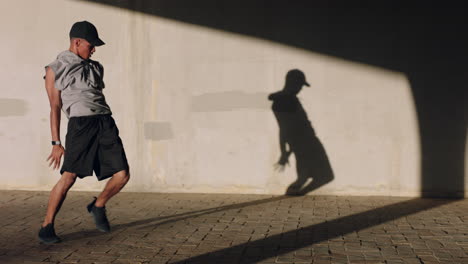 Hombre-Bailando-Joven-Breakdance-Realizando-Movimientos-De-Baile-Estilo-Libre-Backflip-Ajuste-Macho-De-Raza-Mixta-Practicando-En-La-Ciudad-Al-Atardecer-Con-Sombra-En-La-Pared