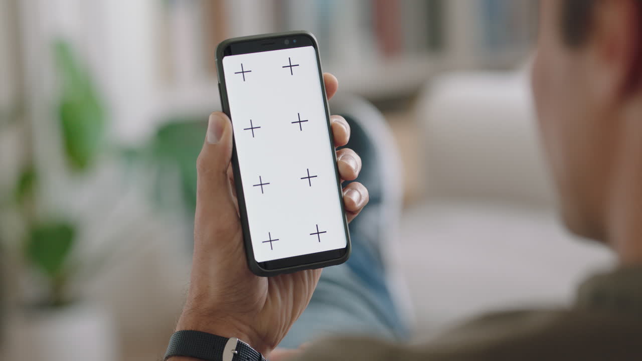 giovane uomo che usa uno smartphone che ha una chat video agitando la mano sullo schermo verde che si gode di chattare sul telefono cellulare display chiave croma orientamento verticale 4k
