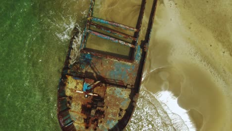 Vista-Aérea-De-Drones-De-Arriba-Hacia-Abajo-Oxidado-Naufragio-En-La-Playa-De-Manzanillo-Con-Olas-En-La-Costa-Arenosa,-Costa-Rica-4k