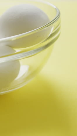 video of close up of glass bowl with eggs on yellow background