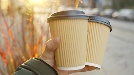 Person-bring-take-away-coffee-cup-for-friend-or-lover-on-sunny-day,-POV