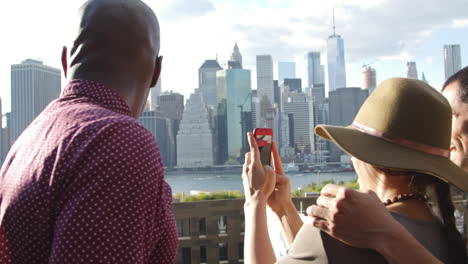 turista tomando una foto del horizonte de manhattan en el teléfono móvil