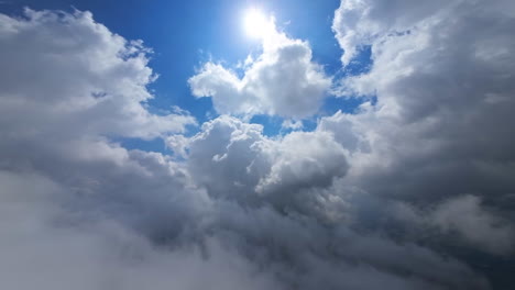 flying in the white clouds. sun is covered and uncovered from cloud. low angle view. fpv drone footage.