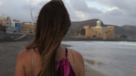 Toma-Cinematográfica-De-Primer-Plano-De-Una-Mujer-Caminando-Y-Admirando-El-Auditorio-Alfredo-Kraus-Desde-La-Playa-De-Las-Canteras,-En-La-Isla-De-Gran-Canaria