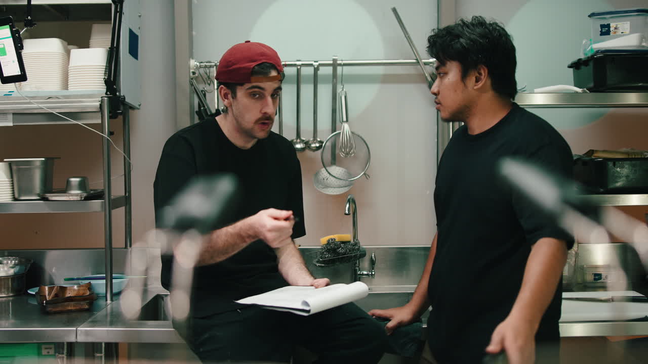 Two Men Discussing Food in a Kitchen