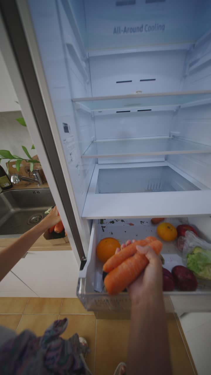 Person organizing vegetables and fruits inside an empty refrigerator