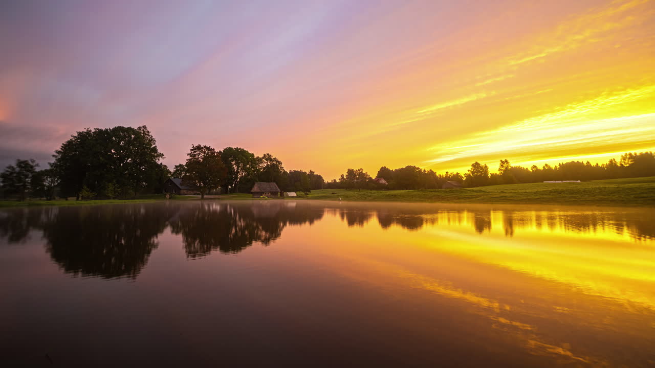 el rocío de la mañana y las nubes pasan sobre un lago antes de que un amanecer naranja anuncie el día