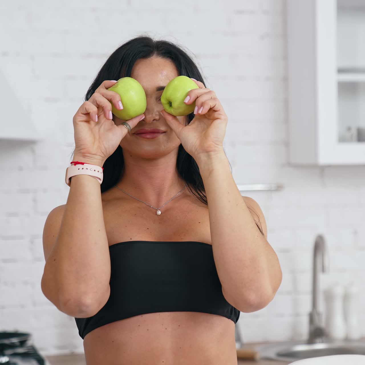 Donna felice in cucina che gioca con una mela. Una casalinga che fa una colazione sana.