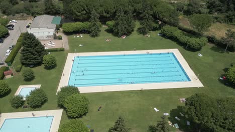 aerial rotational of an outdoors swimming pool with swimmers having fun