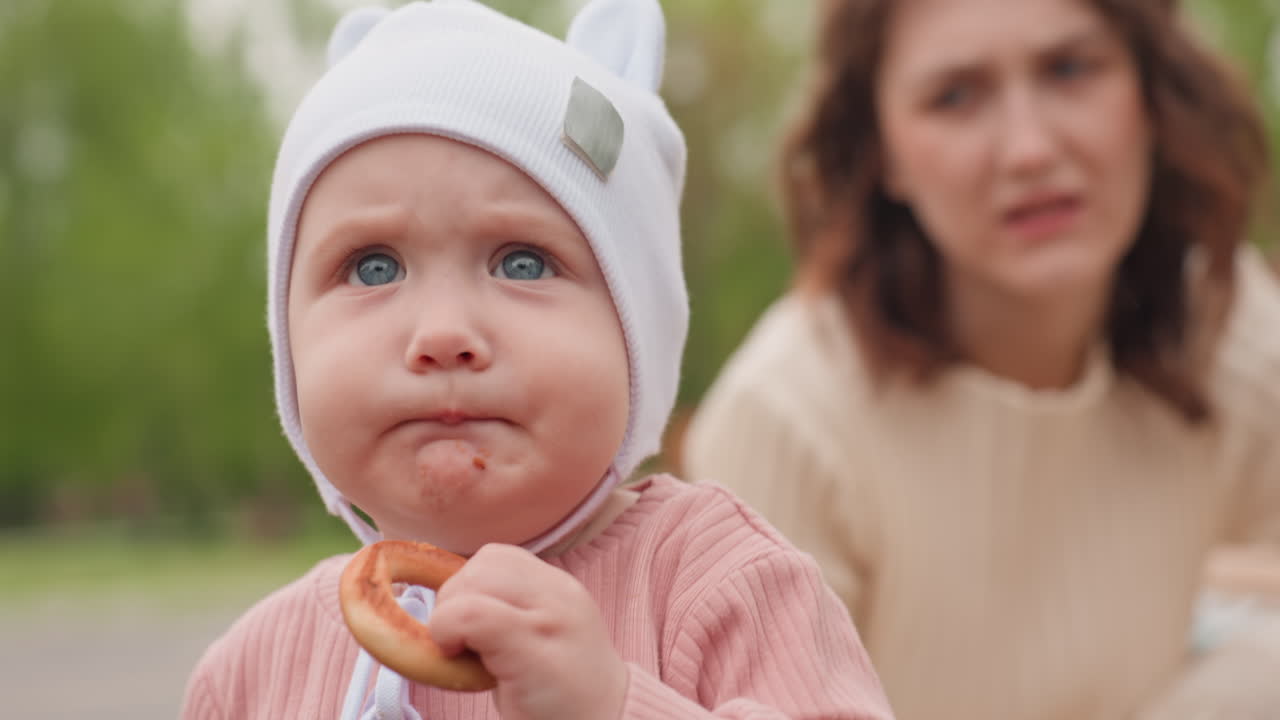 Child Savoring Sweet Treat, Caucasian Child Happily Holding Donut In Outdoor Park Scene, Adorable Infant With Crumbs Around Mouth Enjoying Delightful Snack Outdoors In Vibrant Park Environment