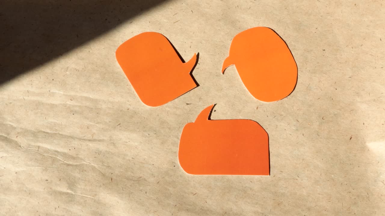 4k video, close-up of three speech bubbles cut out of orange paper, with space for text. Rotate on brown kraft paper, top view. DIY concept