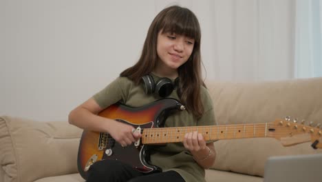 cheerful teen girl learns to play the guitar