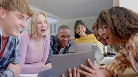 Happy-diverse-group-of-teenage-friends-studying-at-table-with-tablets-at-home,-slow-motion