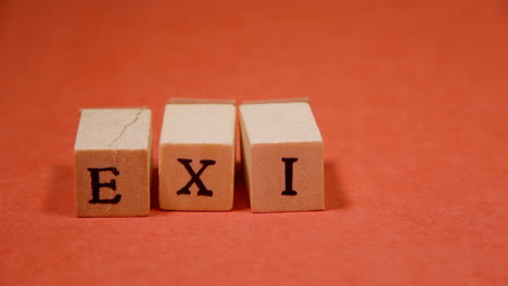 Composing-the-word-Exit-with-wooden-letters-on-a-red-background