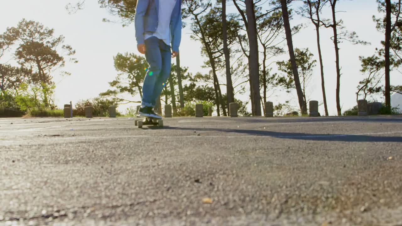 시골 도로 4k에서 스케이트보드를 타고 있는 젊은 남성 스케이트보더의 앞면