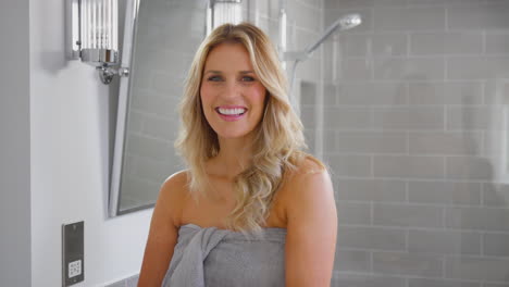 Portrait-Of-Mature-Woman-Getting-Ready-In-Bathroom-At-Home-Wearing-Towel