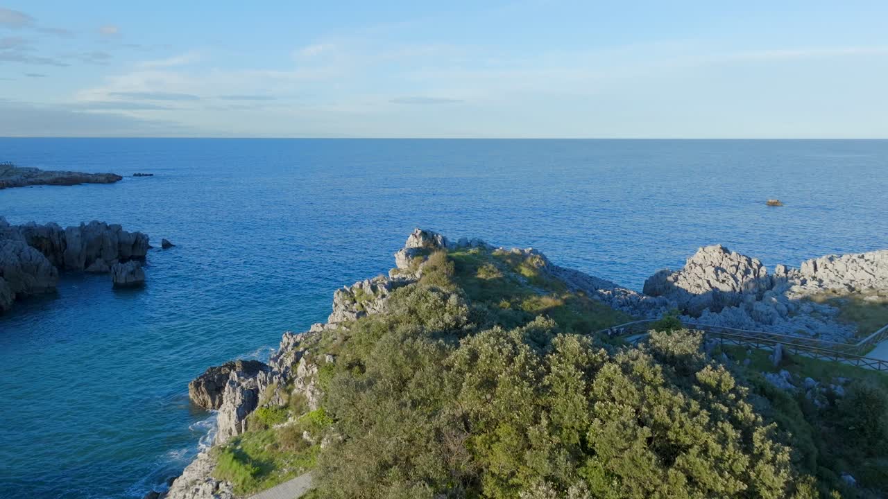 drone sobrevuela la formación rocosa de la península por la playa de el sable hacia el mar de cantabria, españa
