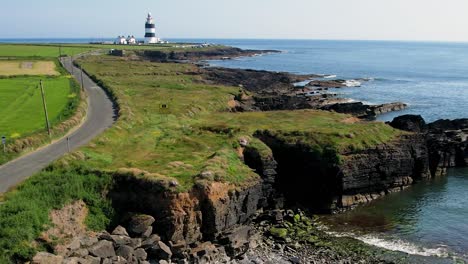 a push forward drone shot of hook head ~lighthouse standing on an outcrop of rock on the wexford coast ireland