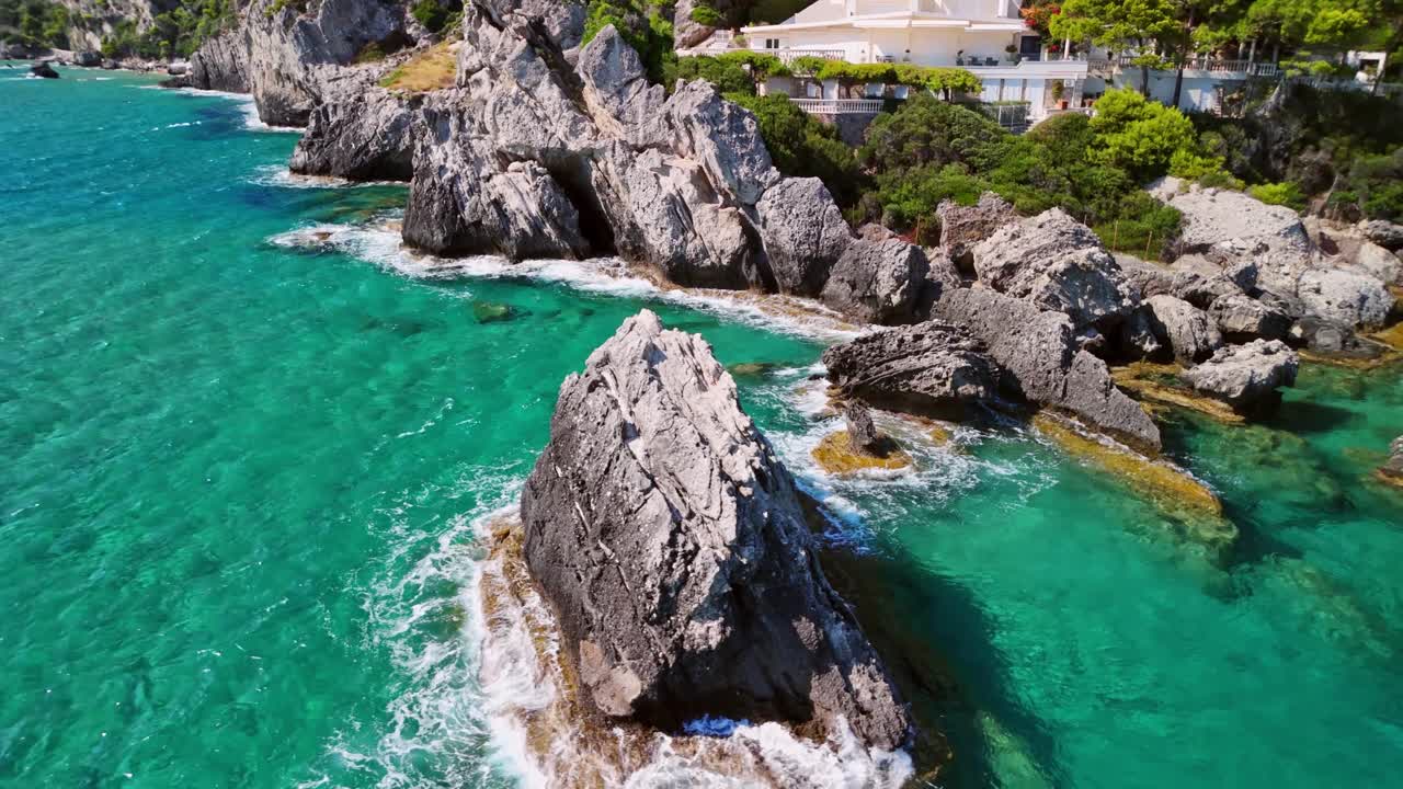Aerial view of rocky coast with turquoise waters and lush green hills