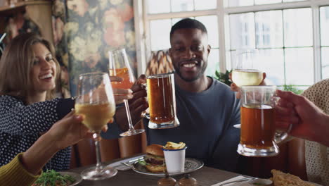 group of friends making a toast as they meet for meal in traditional english pub