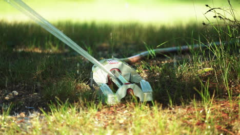 Close-Up-of-Oscillating-Sprinkler-Hydrating-Outdoor-Grass-Lawn