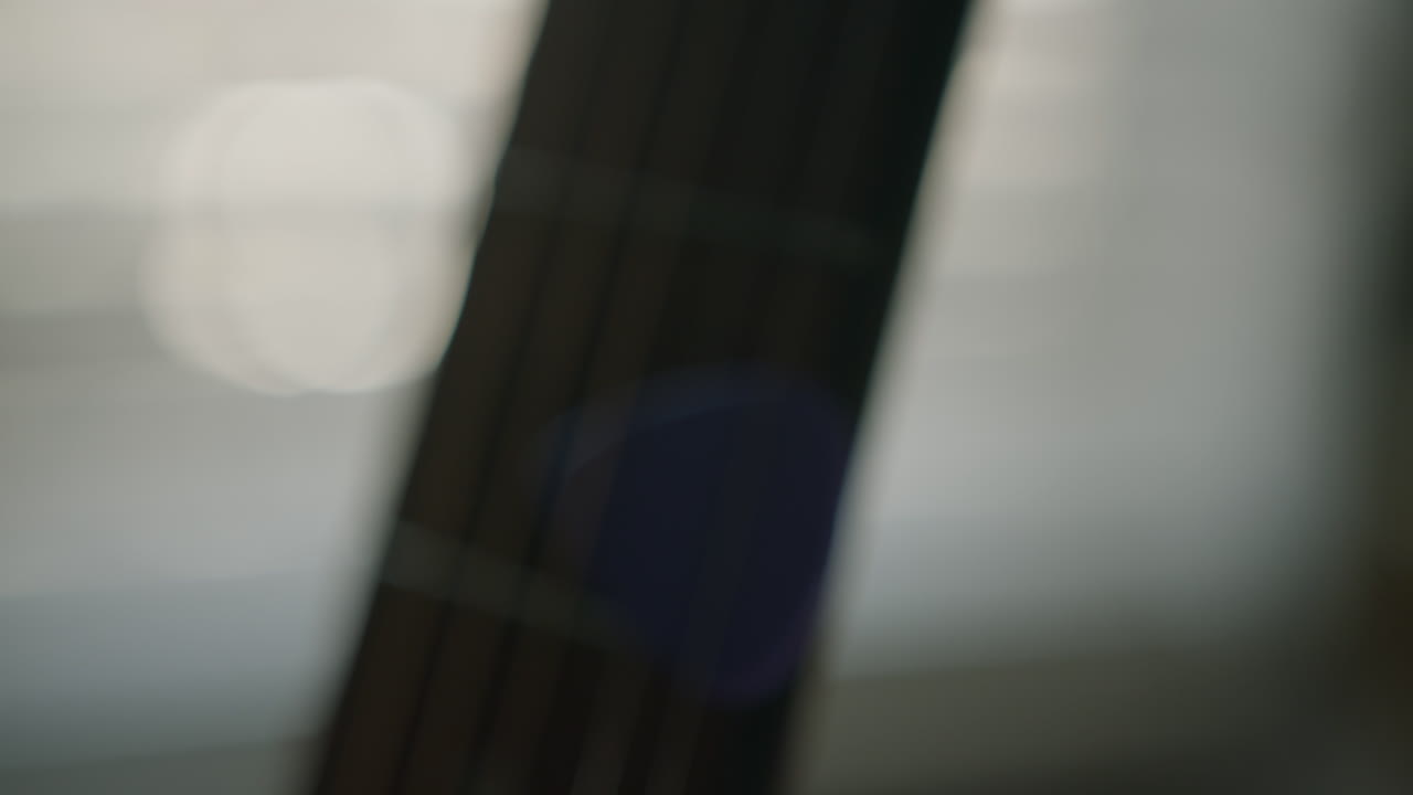 Defocused - camera pushes in on guitar fretboard with pick wedged in strings until they are in focus