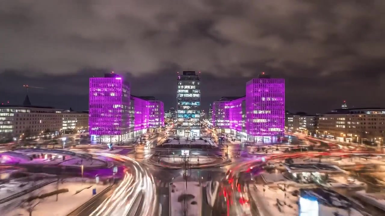 Upea yöllinen näkymä urbaanista kaupunkimaisemasta, jota valaisevat eloisat pinkit valot, esitellen modernia arkkitehtuuria lumisen maiseman keskellä.