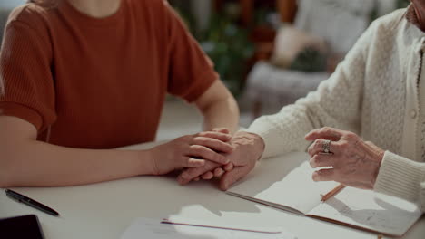 close up of woman and grandmother holding hands during conversation