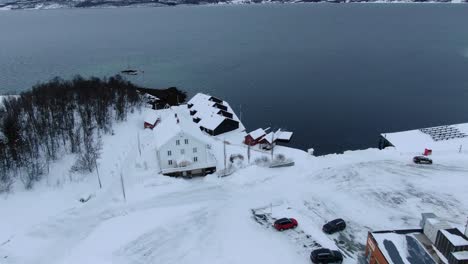 drone view in tromso area flying over finnsnes in winter and showing the sea next to the snowy town with a hotel in norway