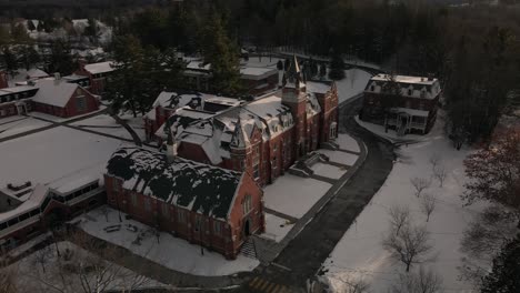 aerial view of bishop's university with snow in sherbrooke, quebec during winter - orbiting drone shot