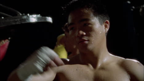 two boxers punch speed bags in a gym