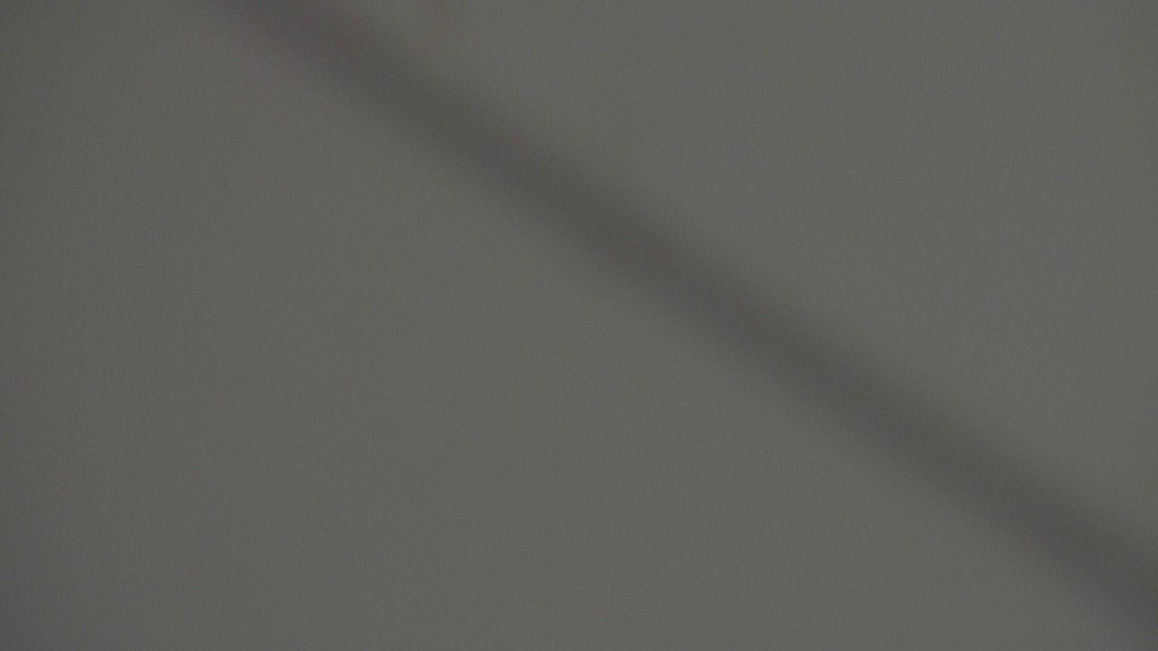 Single white puzzle pieces falling down and spinning in slow motion behind a gray background. Falling in and out of focus with shallow depth of field