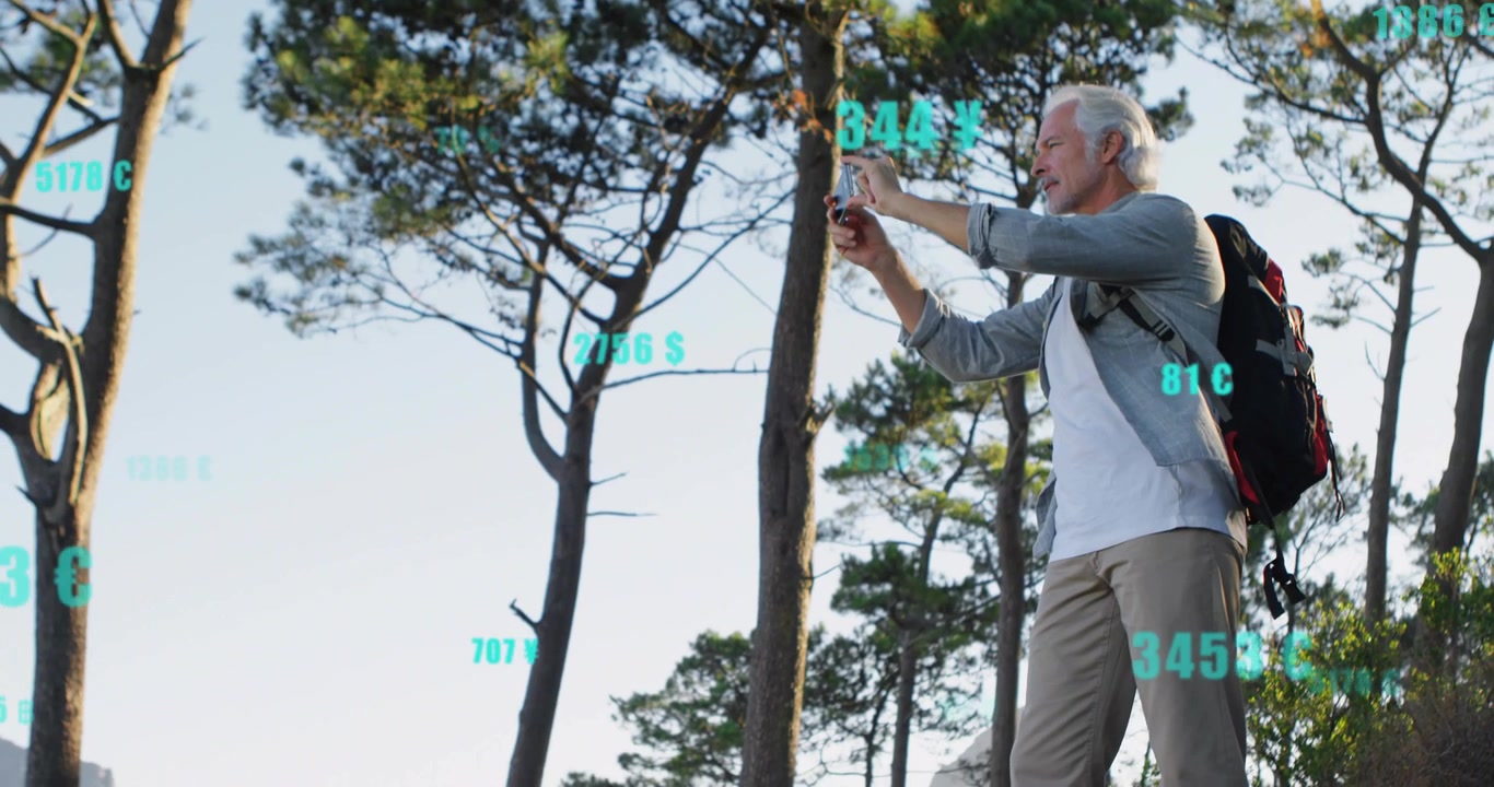 Senior male hiker raising smartphone to capture travel scene, teal numeric overlays tracking phone