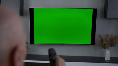 hombre anciano cambia de canal en chroma key tv usando control remoto