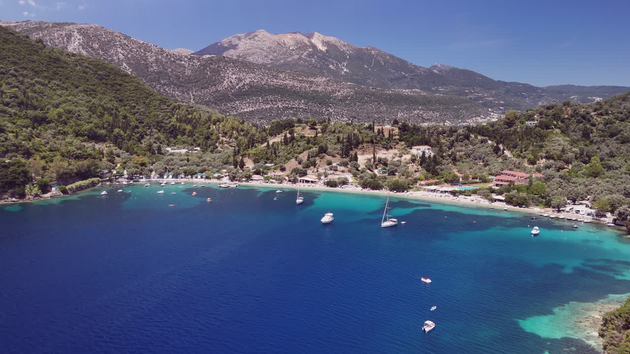 Flyover forested hillside toward Desimi Beach crescent in west Greece
