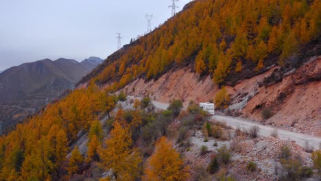 motorhome conduciendo en una carretera de la ladera de la montaña con árboles de color otoño