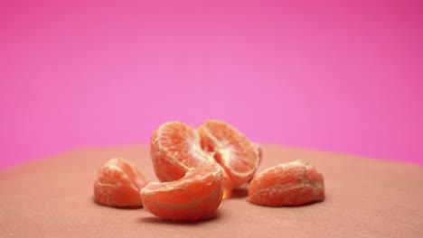ripe peeled mandarin, rotate on pink and old paper background 4k video with color correction