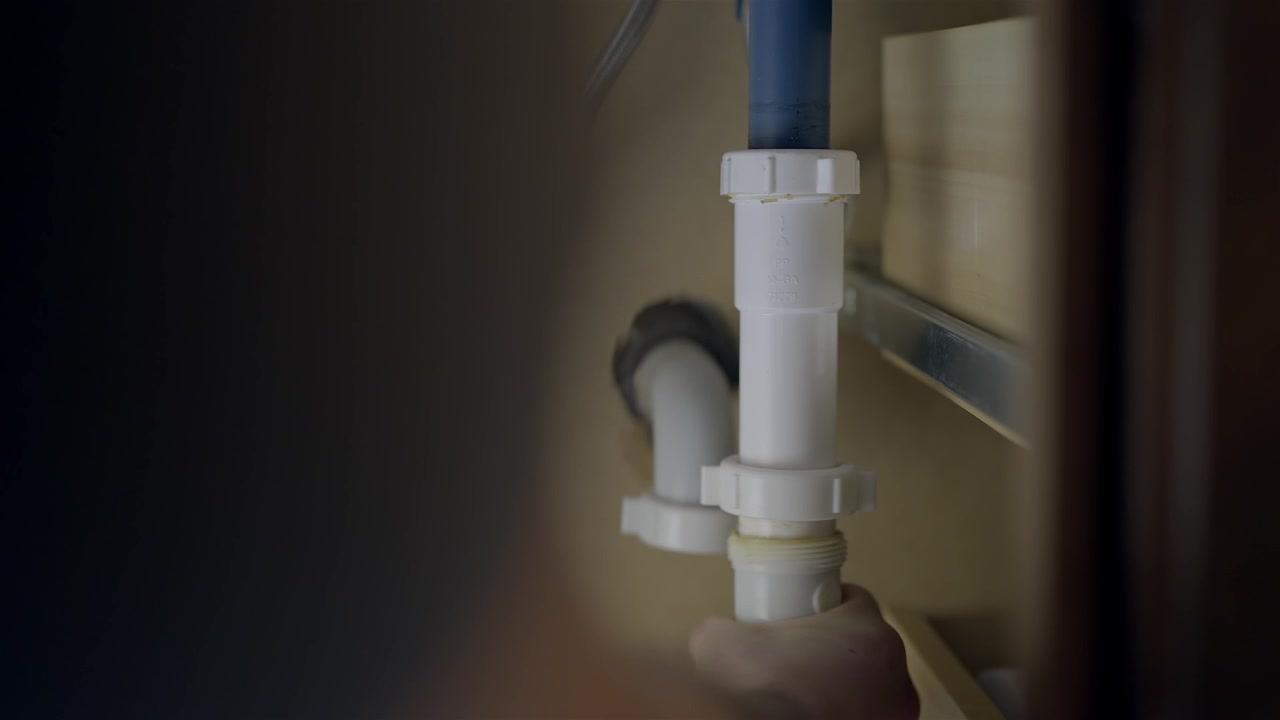 Hand Tightening White PVC Pipe Under Kitchen Sink Repair