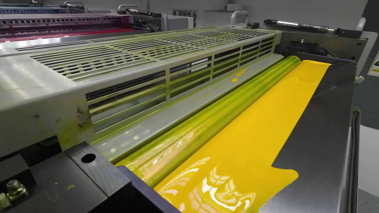 Close-up of a printing press roller covered in vibrant yellow ink