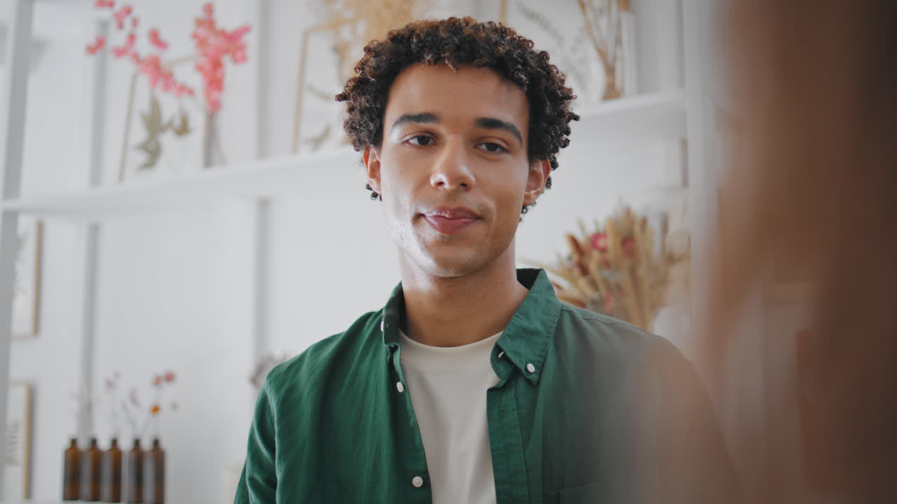 un chico africano relajado hablando en una tienda de flores. un hermoso hombre moreno sonríe.
