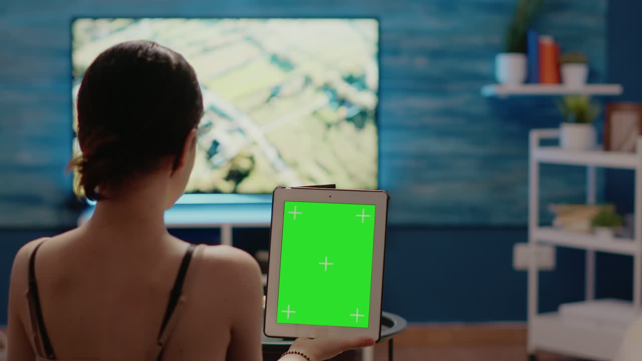 Caucasian woman holding green screen vertically on digital tablet